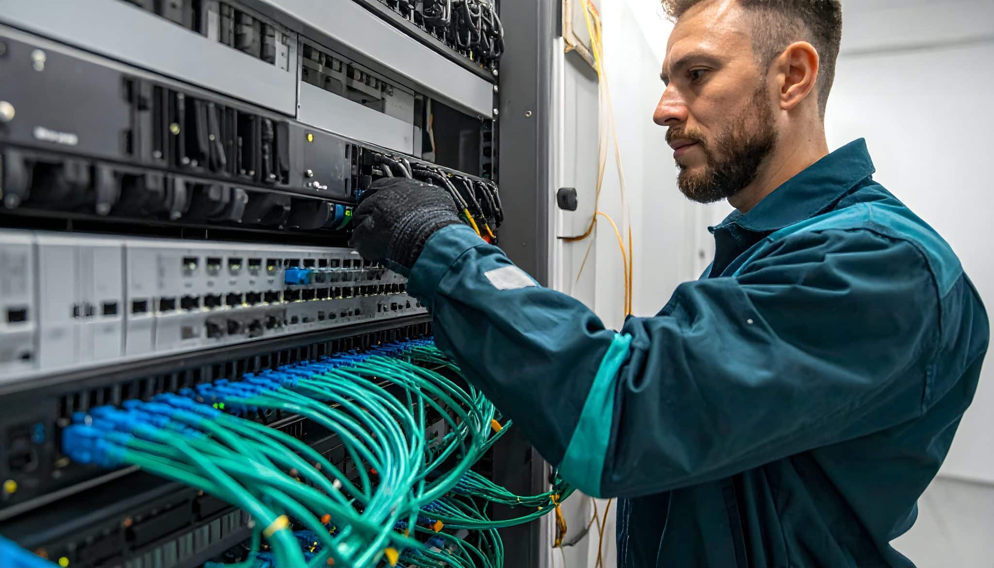 Technician arranging Ethernet patch cables in a commercial network rack