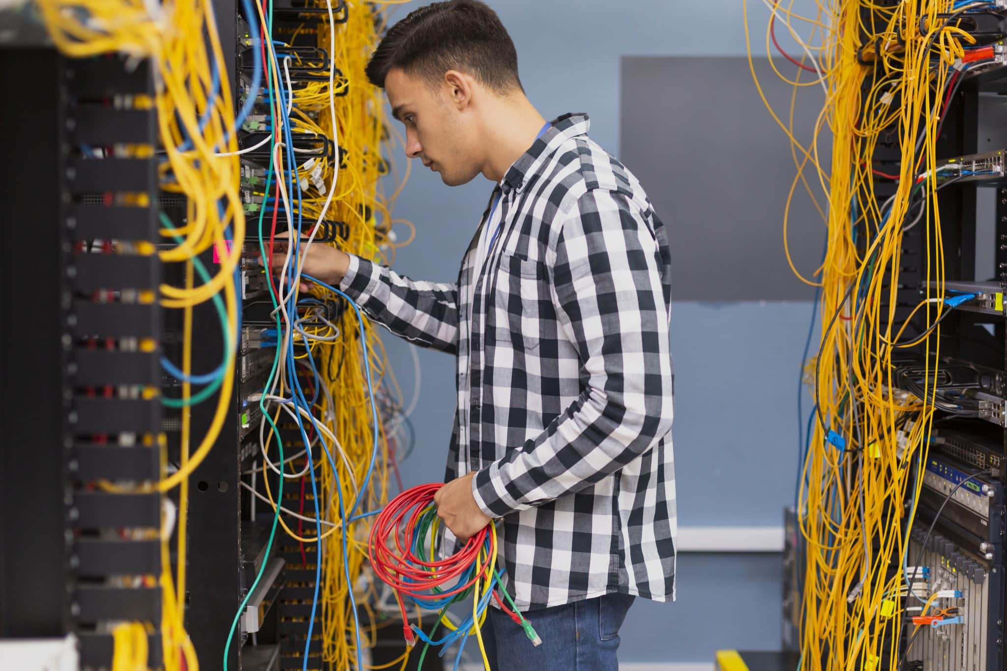 Technician handling Ethernet patch leads beside a network cabinet