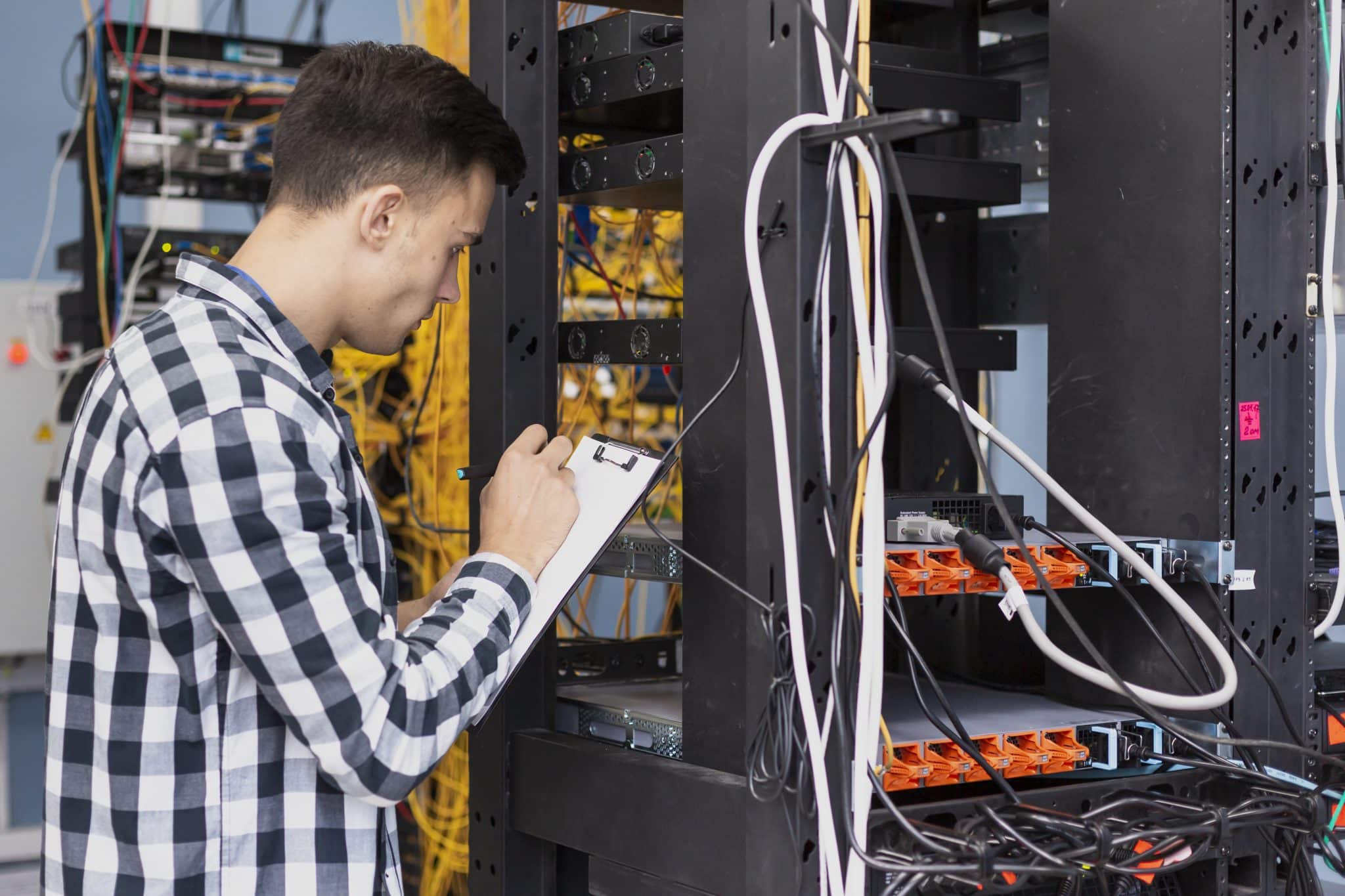 Technician recording network cabinet and cabling observations on a clipboard
